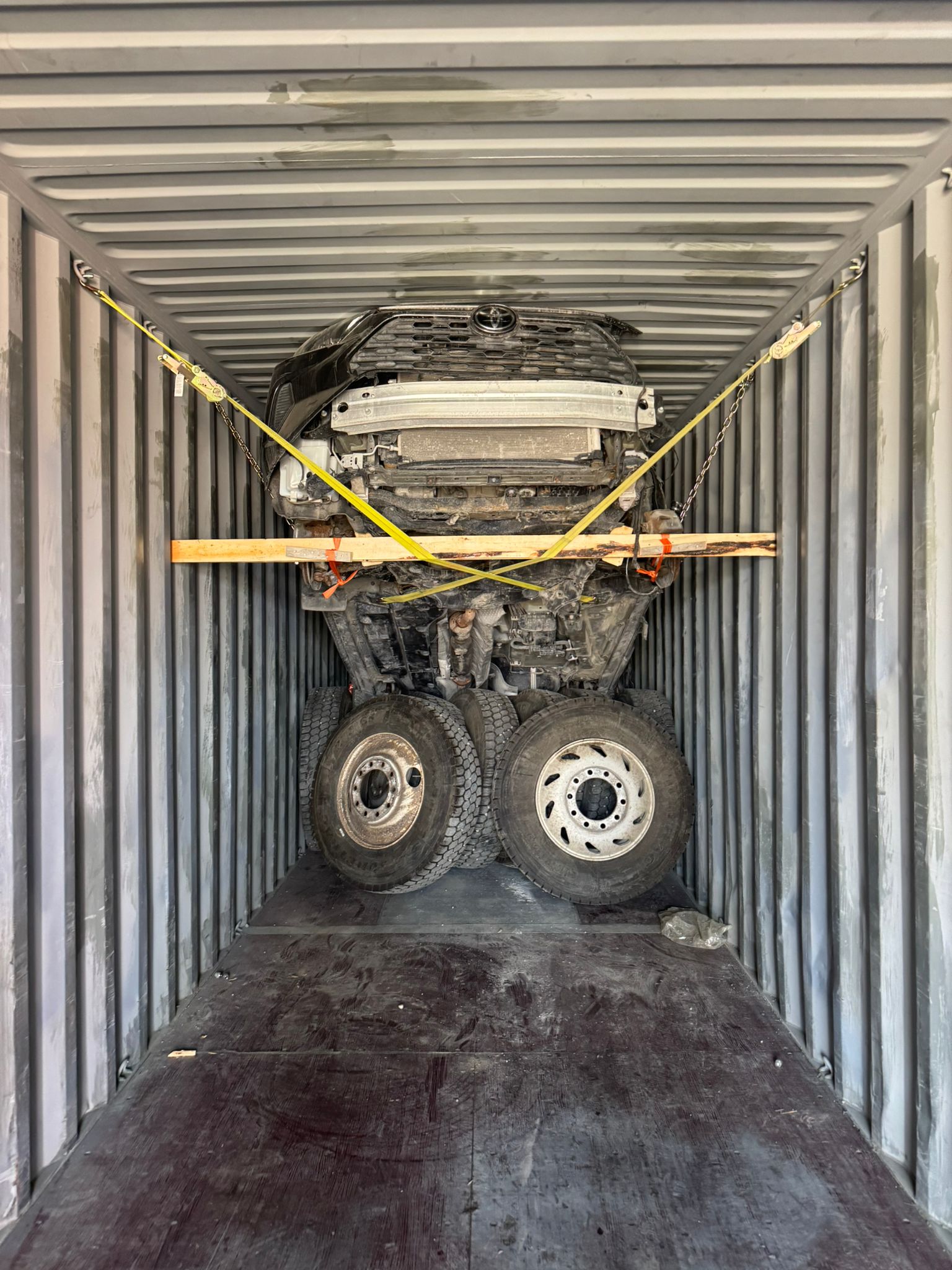 Vehicle secured with straps and wooden bracing inside a shipping container