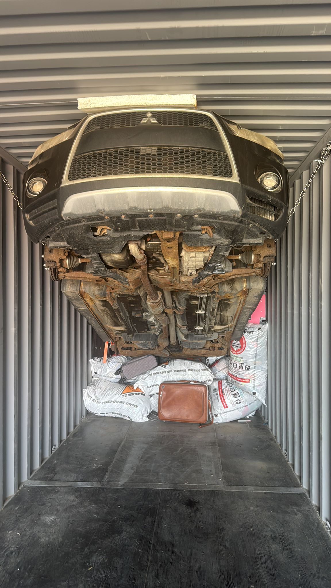 Non-running vehicle lifted and secured inside a shipping container using professional rigging